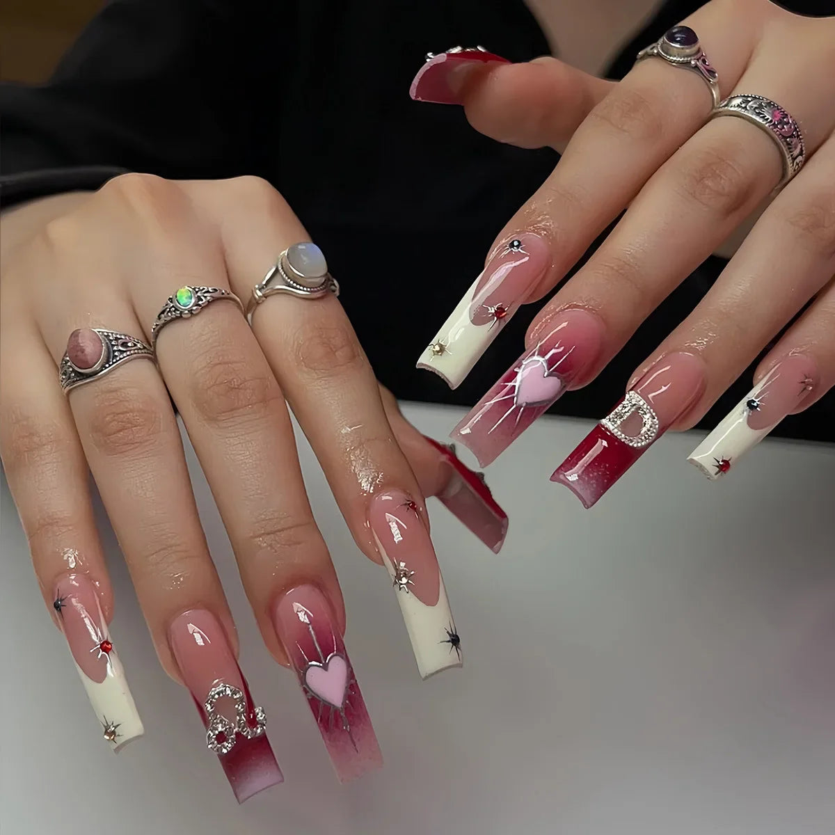 Long square false nails with white French tips, pearl bow designs, and nude pink accents.